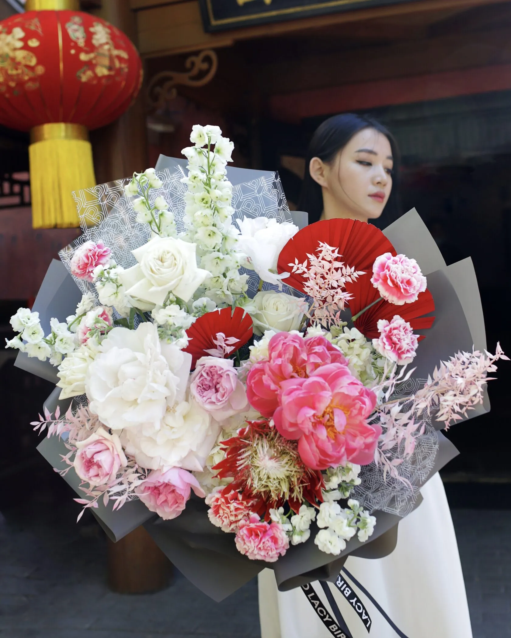 Florist holding a large Lacy Bird style bouquet with peonies and red fans